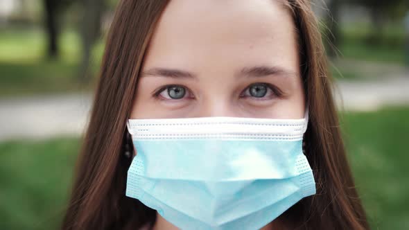 Closeup Face Young Woman Looking at the Camera in Protective Medical Face Mask Being Outdoors During