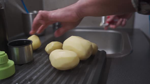 A Man Peels Potatoes with a Special Vegetable Peeler