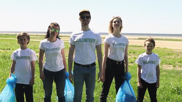 Group Portrait of Joyful Adult and Kids Showing Thumbs Up Staying with Plastic Bottle Rubbish Bags