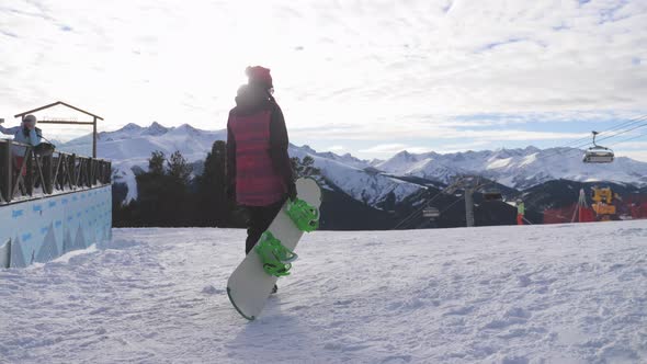 Girl Snowboarder with Snowboard on Mountain Top on Ski Resort. Winter Sports and Winter Vacation