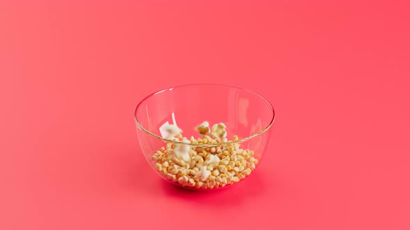 Corn seeds popping up from glass bowl. Popcorn preparation.Delicious salty snack