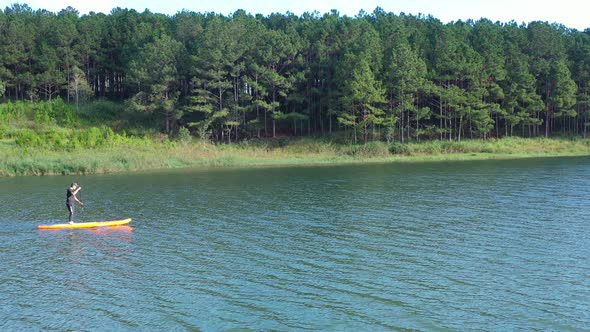 Aerial drone view of man is paddling on stand up paddleboarding in the mountain lakes