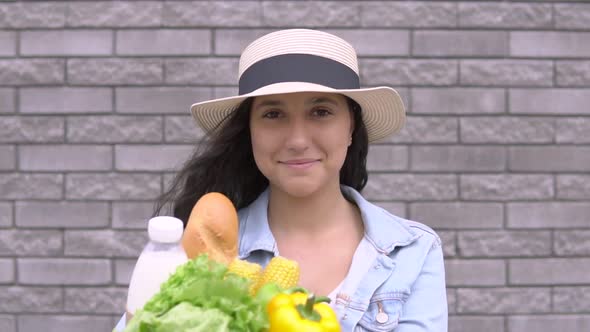 A Young Beautiful Woman in a Denim Jacket and Hat Is Holding a Package with Products