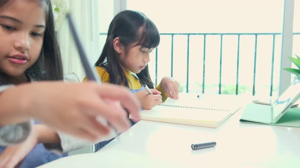 Two happy cute asian female children using laptop for remote education