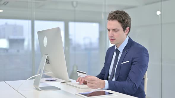 Focused Young Businessman Making Online Payment on Desk Top