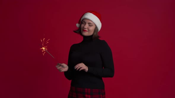 Trendy Hipster Girl in Santa Hat Dancing with Bengal Sparkler Fire on Red 