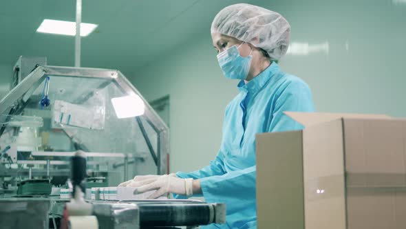 Asian Ethnicity Woman Works with Medications on a Conveyor