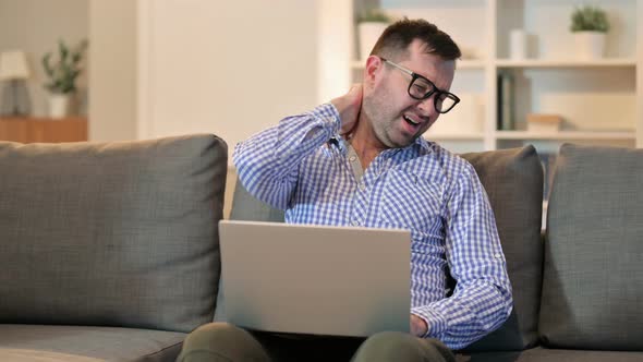 Young Man with Back Pain Using Laptop at Home 