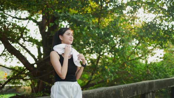 Happy Asian woman running in park on public green background,