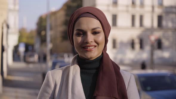 A Young Beautiful Muslim Woman Smiles at the Camera in a Street in an Urban Area  Closeup