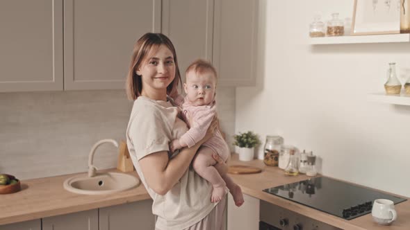 Woman with Newborn Posing in Kitchen