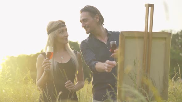 Gorgeous Blond Woman and Handsome Confident Man Standing with Wineglasses at Sunset Outdoors and