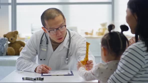 Asian Pediatrician Giving Toy to Little Girl during Consultation