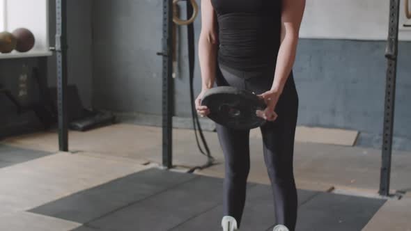 Strong Woman Doing Weighted Plate Lunge in Gym alt