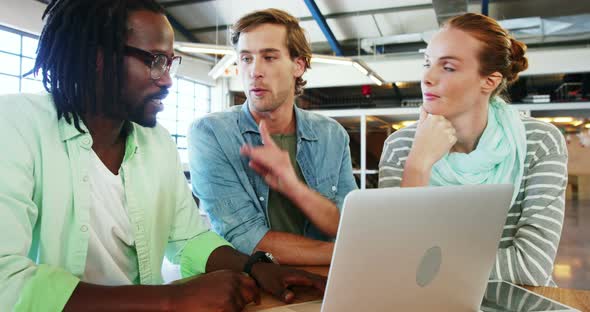 Colleagues interacting with each other over laptop