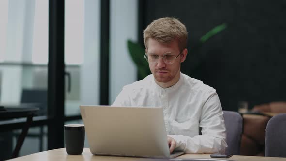 Freelancer Man is Working with Notebook in Cafe or Restaurant in Daytime Coworking Area for Remote