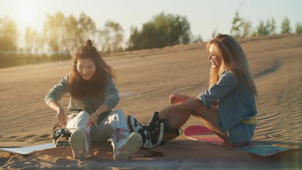Two Pretty Girls with Sandboard in Dubai Desert at Sunset. Summer Vacation, Travel Lifestyle and