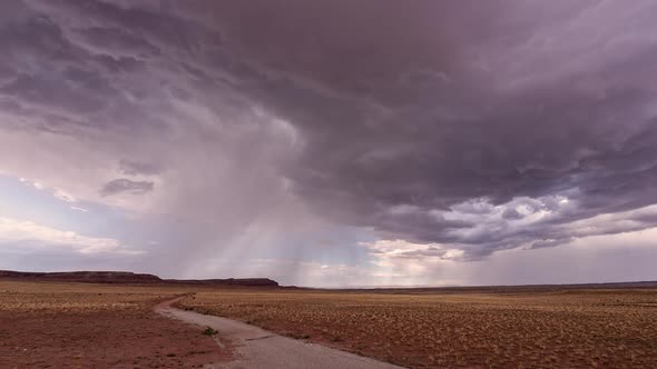 Dirt road leading to storm moving through the Utah desert