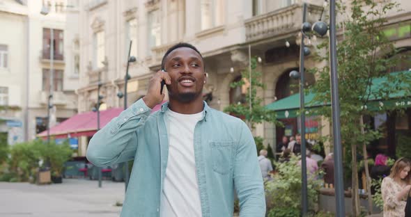 African American Walking Nearby Street Cafes and Enjoying Phone Conversation