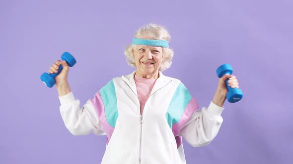 Cheerful Elderly Woman Exercising with a Pair of Dumbbells and Smiling