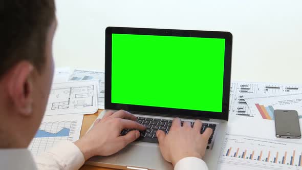 Man Hand on Laptop Keyboard with Green Screen Monitor in the Office