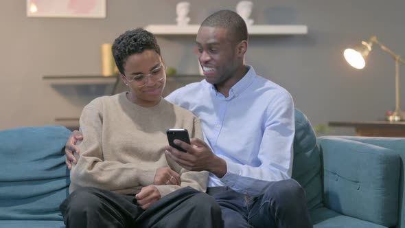 Couple Using Smartphone While Sitting on Sofa