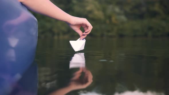 Girl Launching Origami Ship In Water On Sunset. Relaxing And Enjoying Time. Paper Boat On River.