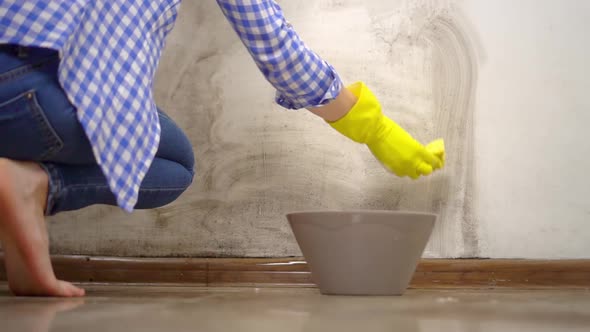 blonde, washes white wall in apartment with foam, sponges in yellow gloves