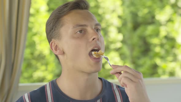 Close-up of Young Brunette Caucasian Man with Brown Eyes Tasting Delicious Baked Shrimp in Outdoor