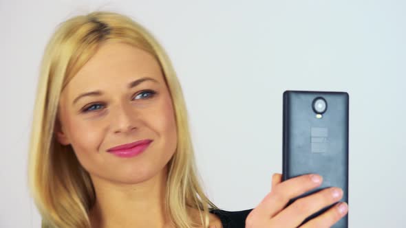 A Young Attractive Woman Takes Pictures with a Smartphone - Closeup - White Screen Studio