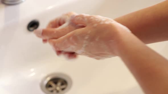 Woman Washes Her Hands in the Bathroom with Water Soap and Foam