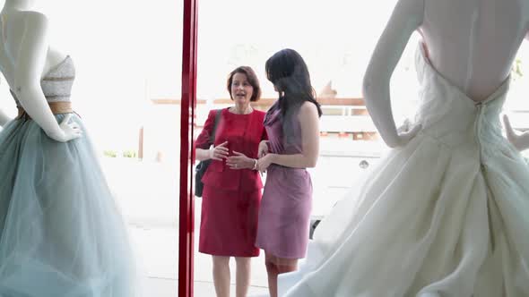 Mother and daughter looking at wedding dress in shop window