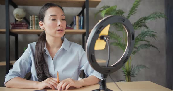 Close Up Portrait of Smiling Asian Teacher Conducts an Online Lesson Using Smartphone