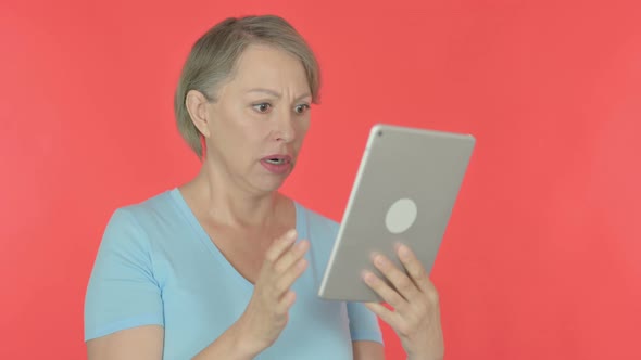 Old Woman Reacting to Loss on Tablet on Red Background