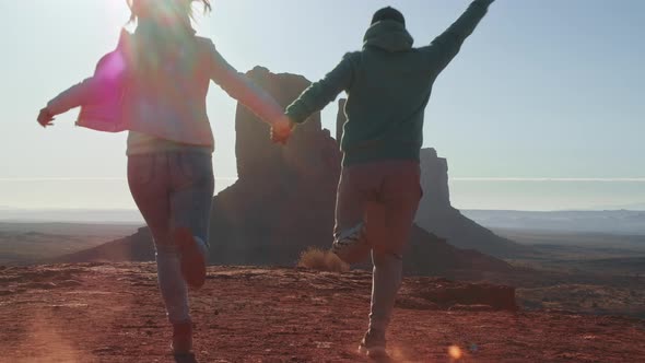Happy Couple on Vacation Trip Running in Monument Valley Jumping Raising Arms