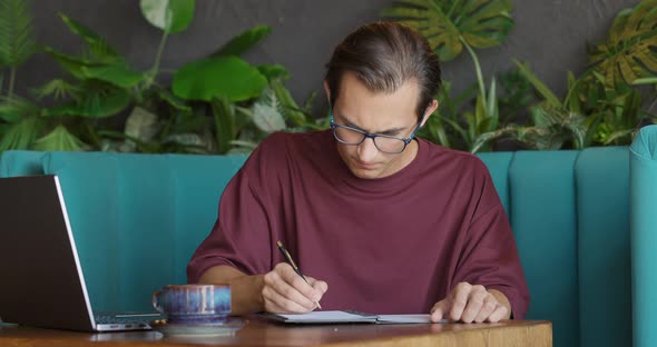 Handsome Young Man in Eyeglasses are Writing and Crumpled Miswritten Paper in Cafe