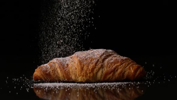 Powdered sugar sprinkling onto a croissant