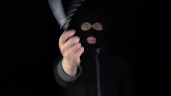 A Man in a Balaclava Mask Holds Out a Butterfly Knife Into the Camera. The Thug Twists a Knife 