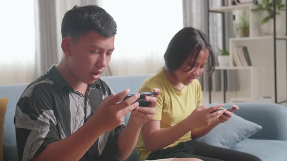 Asian Children Playing Video Games On Mobile Phone At Home