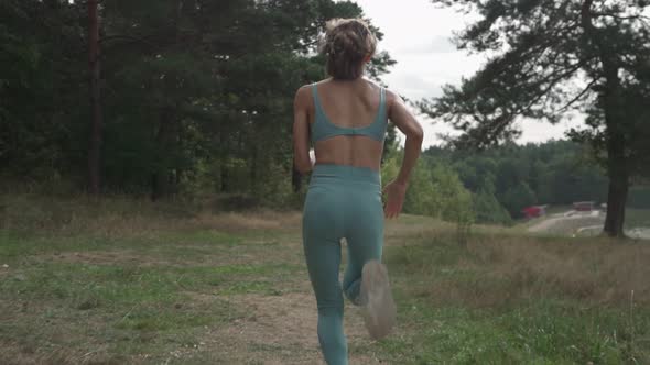 Side View of a Woman Running Uphill in a Forest