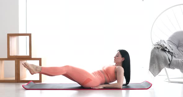 Woman doing abdominal exercises on mat at home.