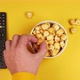 Male hands pick up crispy caramel popcorn from a white plate on a yellow background with a smart tv - VideoHive Item for Sale