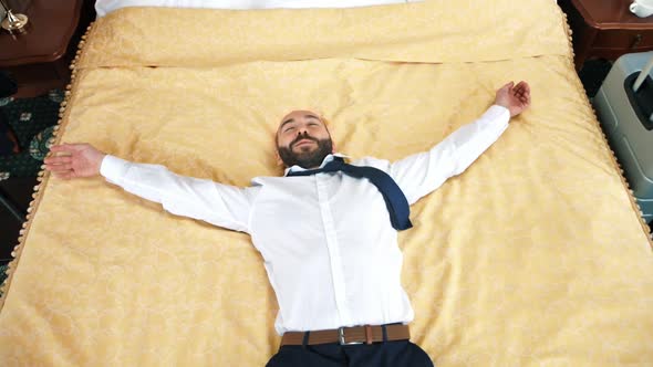 Happy Male Businessman Jumping on Bed at Hotel Room Having Business Trip Slow Motion