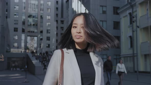 Young Asian Woman Shaking Her Hair and Looking at Camera in the City