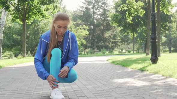 Beautiful Sportswoman Tying Her Shoelaces Before Running in the Park