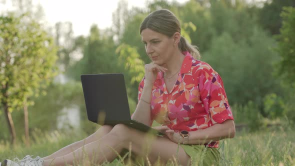 A Middleaged Woman Works Using Her Laptop in a Public Park