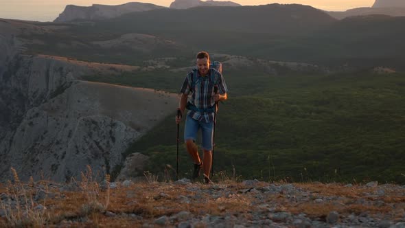 Front View of Young Man Climbing Mountain in Countryside on Autumn Day Spbd