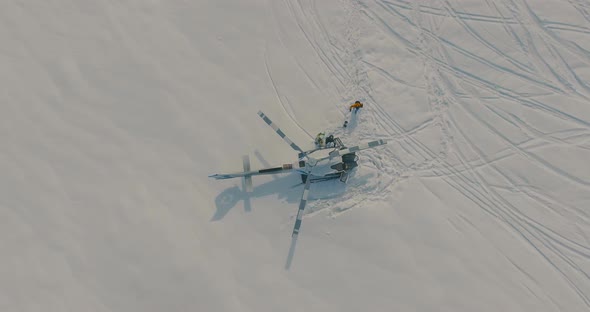 Skiers board a Helicopter Standing in the Snow