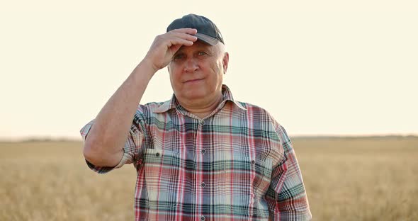 Happy Man in Plaid Shirt Standing in Golden Wheat Field at Sunset