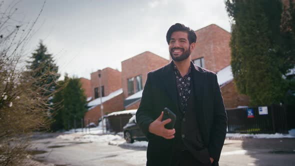 Outside Shot of a Sexy Young Entrepreneur Cuban Bearded Man Looking at His Smartphone and Smiling